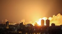 Fire and smoke rising over a city at night after a drone strike.