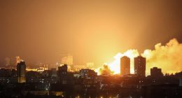 Fire and smoke rising over a city at night after a drone strike.