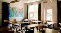 Empty classroom with desks and chairs arranged in rows.