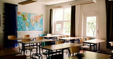 Empty classroom with desks and chairs arranged in rows.