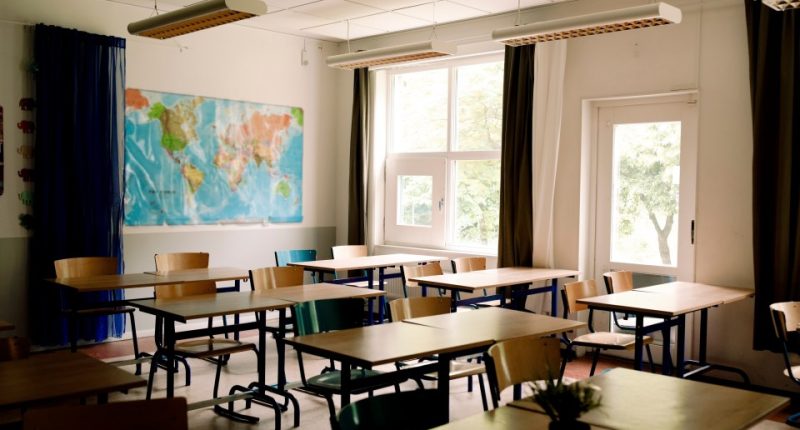 Empty classroom with desks and chairs arranged in rows.