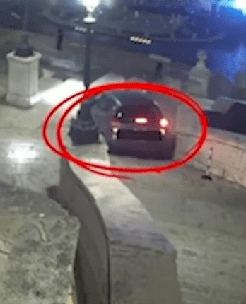 Security camera image of a car at night.