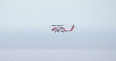 Coast Guard helicopter in flight over water.