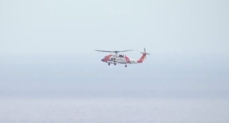 Coast Guard helicopter in flight over water.