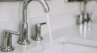 Close-up of water running from a bathroom sink faucet.