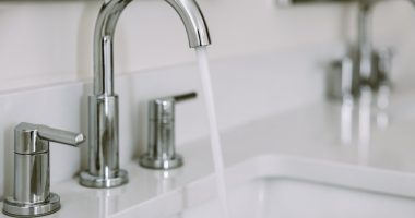 Close-up of water running from a bathroom sink faucet.