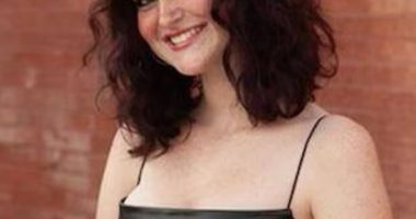 Portrait of a smiling teenage girl wearing a black dress.