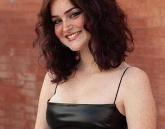 Portrait of a smiling teenage girl wearing a black dress.