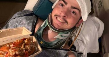 A 19-year-old in a neck brace holds a lobster roll.
