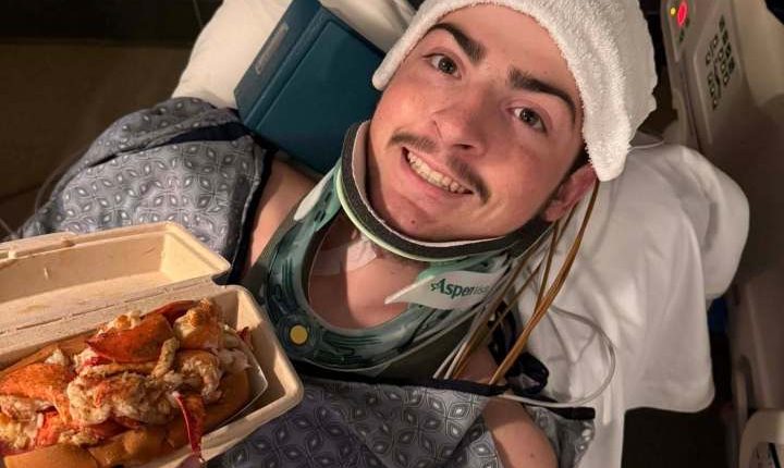 A 19-year-old in a neck brace holds a lobster roll.