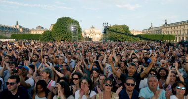 People clap as they gather to listen to music prior to the reinstallation and lift-off of the 2024 Olympic cauldron during a free concert to mark France's annual street music festival, 'Fete de la Musique', at the Jardin des Tuileries, in Paris on June 21, 2025. (Photo by GEOFFROY VAN DER HASSELT / AFP) (Photo by GEOFFROY VAN DER HASSELT/AFP via Getty Images)