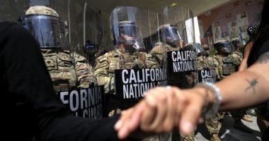 Protesters clasp hands in front of a line of California National Guard, Monday, June 9, 2025, at a Federal Building in downtown Los Angeles. (AP Photo Jae Hong)