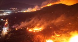 Firefighters battling a large wildfire at night.