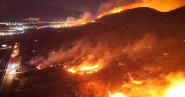Firefighters battling a large wildfire at night.