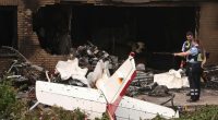 Police officers examining the remains of a plane that crashed into a building.