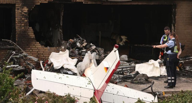 Police officers examining the remains of a plane that crashed into a building.