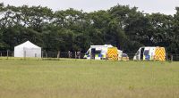 Police and forensic vehicles at a skydiving accident scene.