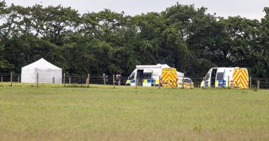 Police and forensic vehicles at a skydiving accident scene.