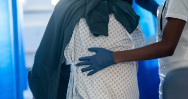 NHS staff guides a patient through a hospital ward