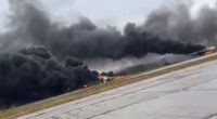 Large plume of black smoke rising from a burning airfield.