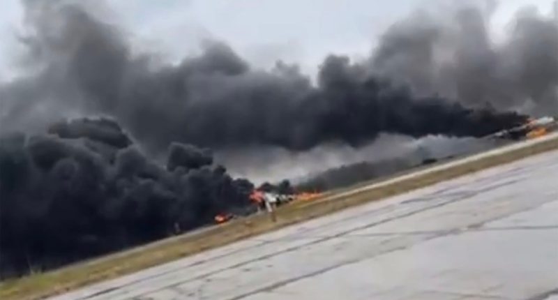 Large plume of black smoke rising from a burning airfield.