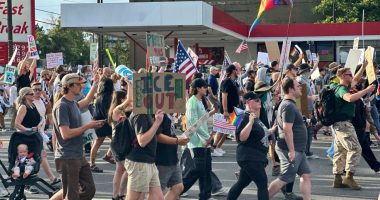 Protestors march carrying signs.
