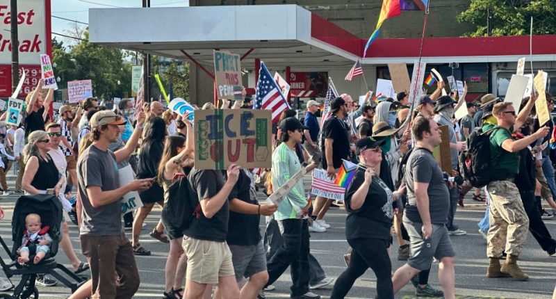 Protestors march carrying signs.