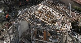 Emergency personnel at a destroyed building after a missile strike.
