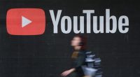A young woman wearing headphones walks past a billboard advertisement for YouTube on September 27, 2019 in Berlin, Germany. YouTube has evolved as the world's largest platform for sharing video clips. (Photo by Sean Gallup/Getty Images)