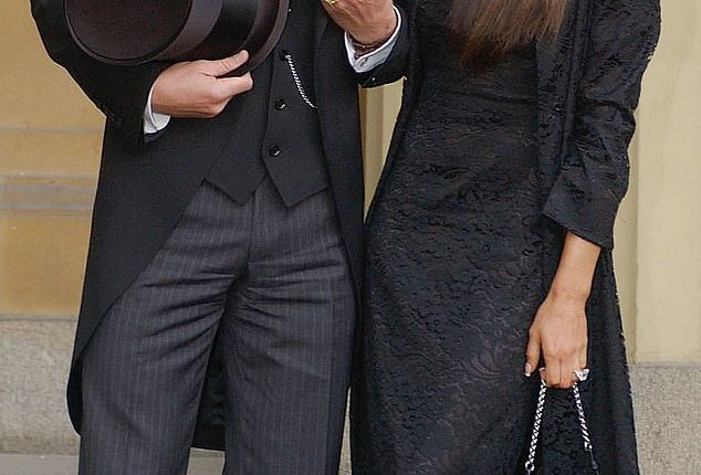 David Beckham stands with his wife Victoria Beckham after receiving his OBE in 2003