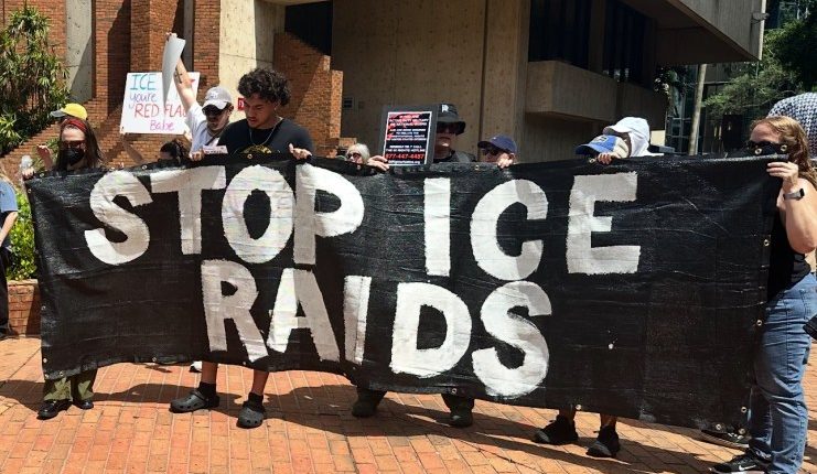protesters holding a banner reading STOP ICE RAIDS