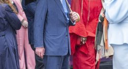 King Charles attempted to keep himself dry in the typical British wet weather by holding up a large brolly as he strolled through the streets of Shoreditch