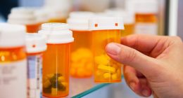Hand holding a prescription pill bottle.