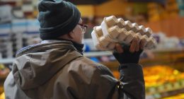 Person holding a carton of eggs in a supermarket.