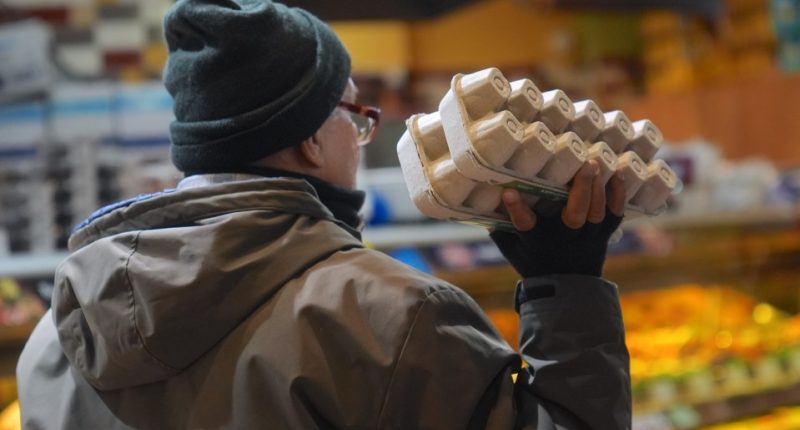 Person holding a carton of eggs in a supermarket.