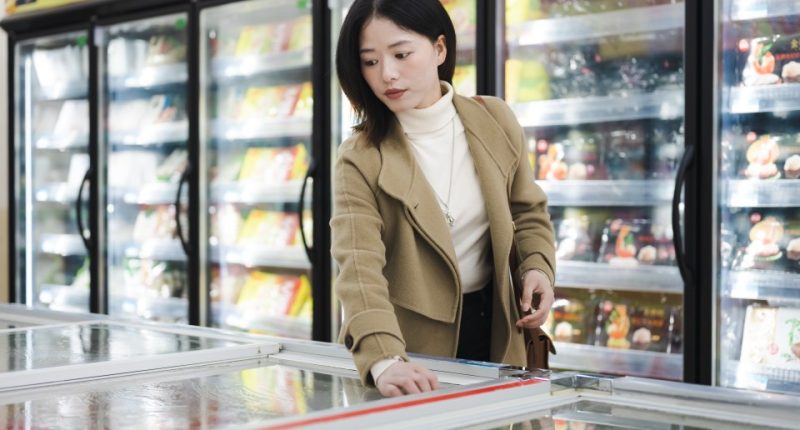 Woman shopping for frozen food in a supermarket.