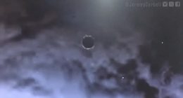Disc-shaped object in cloudy sky.