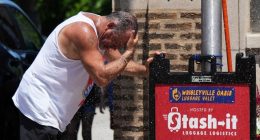 Man cooling off under a sprinkler during hot weather.