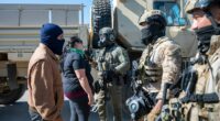 Federal immigration agents talk to Rebecca Torres, second left, after she tried to block a military vehicle during a raid in the agriculture area of Camarillo, Calif., Thursday, July 10, 2025. (AP Photo/Michael Owen Baker)