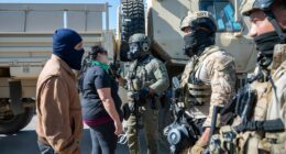 Federal immigration agents talk to Rebecca Torres, second left, after she tried to block a military vehicle during a raid in the agriculture area of Camarillo, Calif., Thursday, July 10, 2025. (AP Photo/Michael Owen Baker)