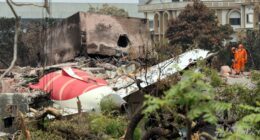 Debris from a plane crash site with rescue workers.