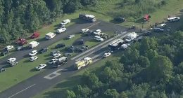 Aerial view of emergency personnel and vehicles at an airport runway after a small aircraft crash.