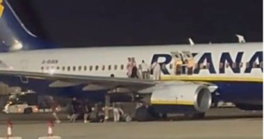Passengers evacuating a Ryanair plane on the tarmac.