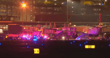 Emergency vehicles surrounding an airplane on an airport tarmac at night.