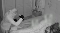 Security camera footage of a burglar looking at a sleeping woman.