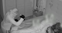 Security camera footage of a burglar looking at a sleeping woman.