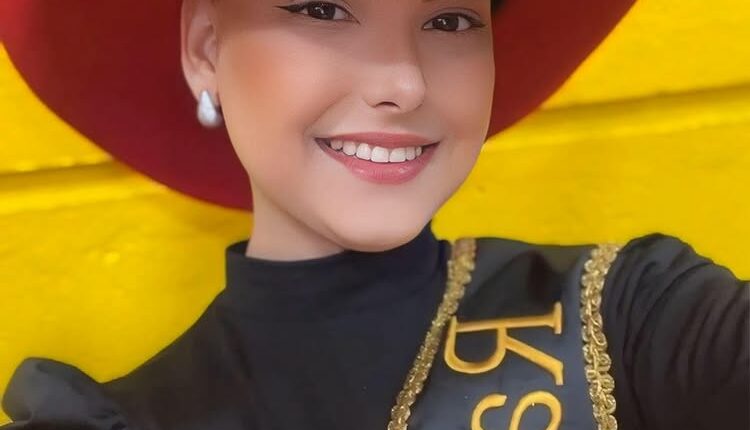 Portrait of Camila Trevisol, a rodeo queen, wearing a red cowboy hat and sash.
