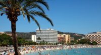Crowded beach in Magaluf, Mallorca, with hotels in the background.