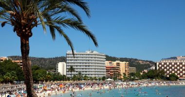 Crowded beach in Magaluf, Mallorca, with hotels in the background.
