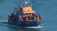 Migrants entering the water from a small boat.